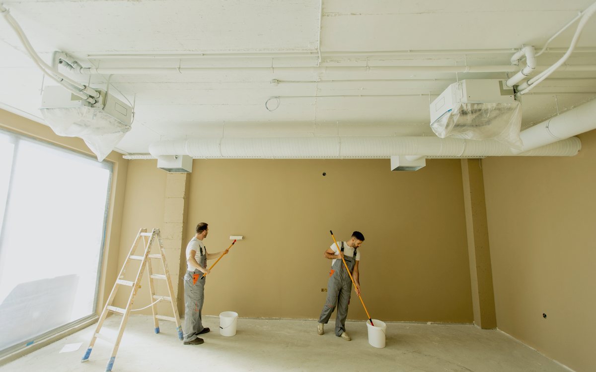 Two painters finishing the walls of a commercial suite during a tenant improvement build out