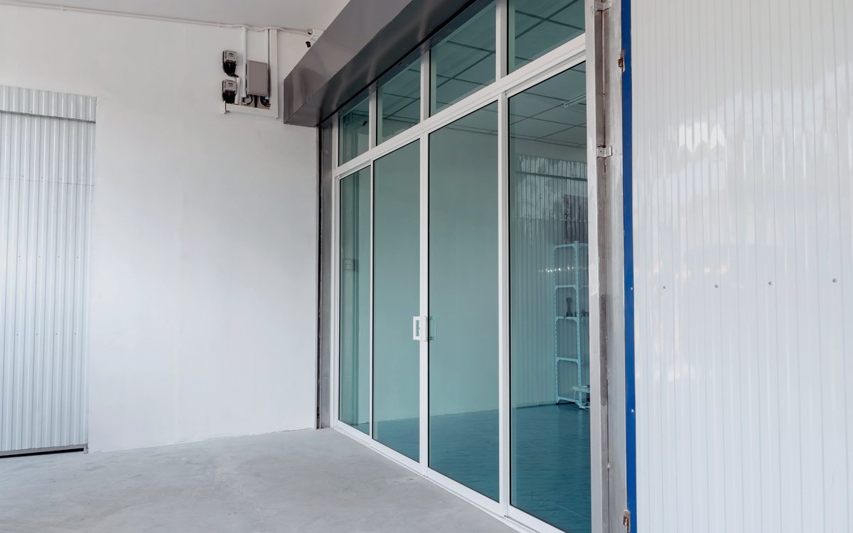 Wall of glass sliding patio doors installed in a finished room, opening the interior to the outdoors