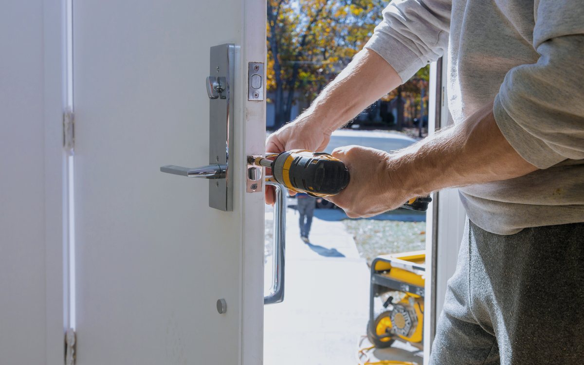 Installer fitting a handleset and latch into a new exterior door, adjusting the hardware so it closes cleanly