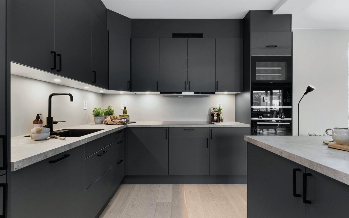 Contemporary graphite gray kitchen with handleless slab cabinets, under cabinet lighting, and a light quartz countertop