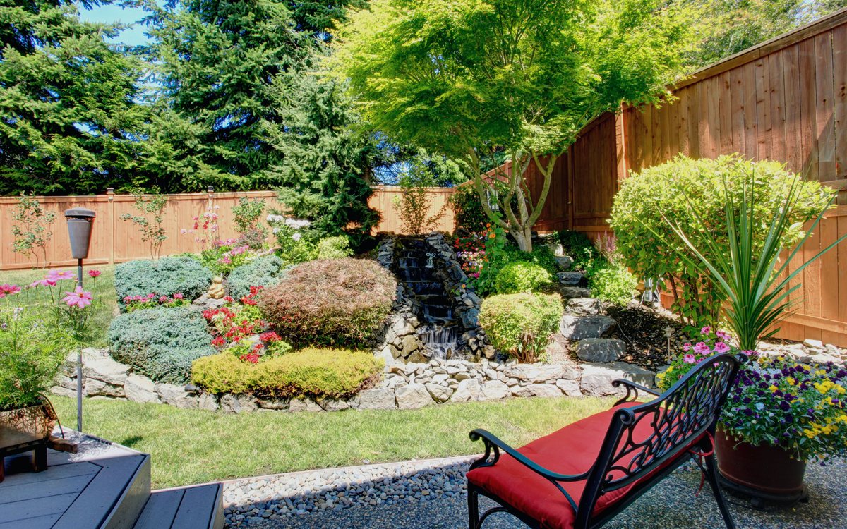 Landscaped garden with a stone water feature, mixed shrubs, and low voltage path lighting