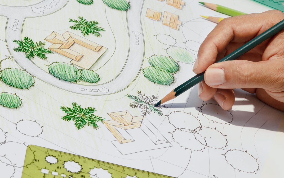 Hand drawing a landscape design plan showing planting beds, paths, and hardscape areas