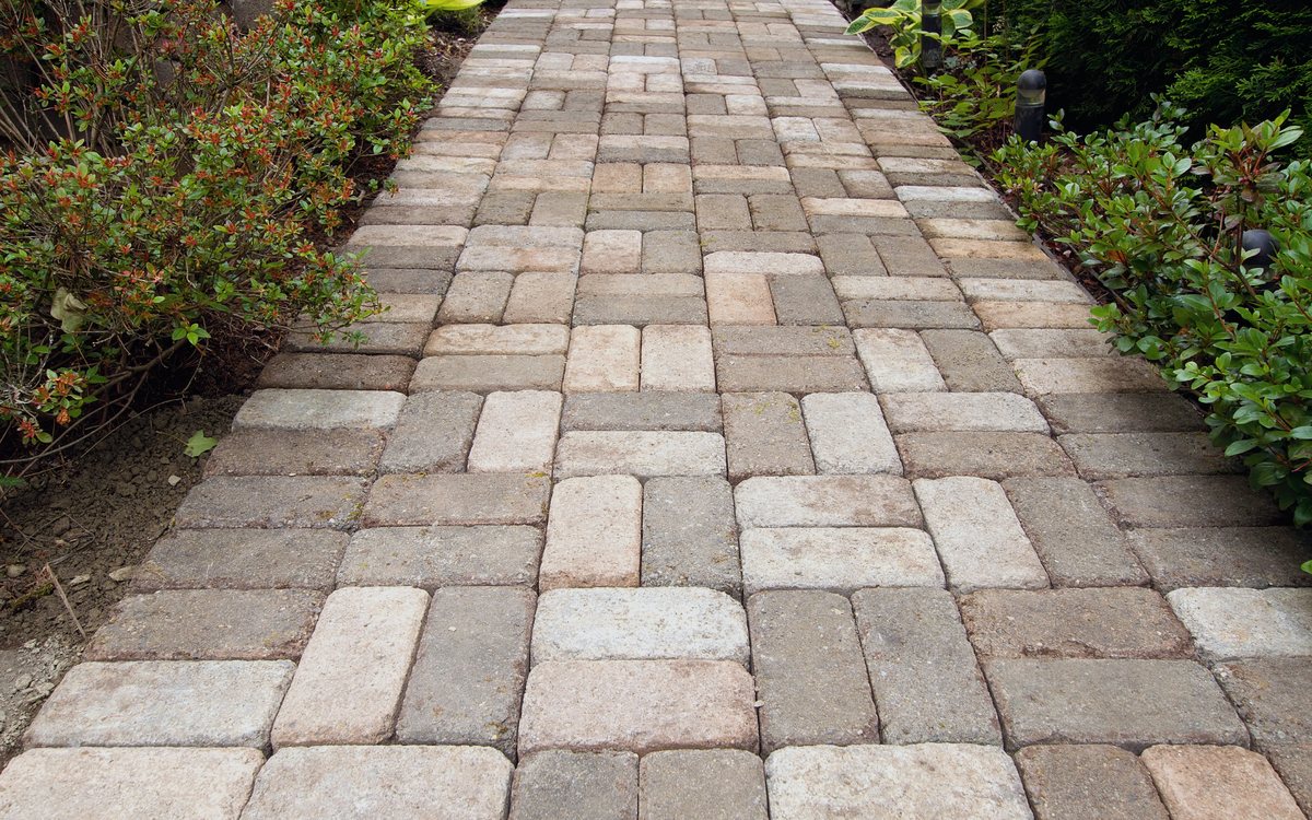 Tumbled stone paver walkway running between planting beds in a running bond pattern