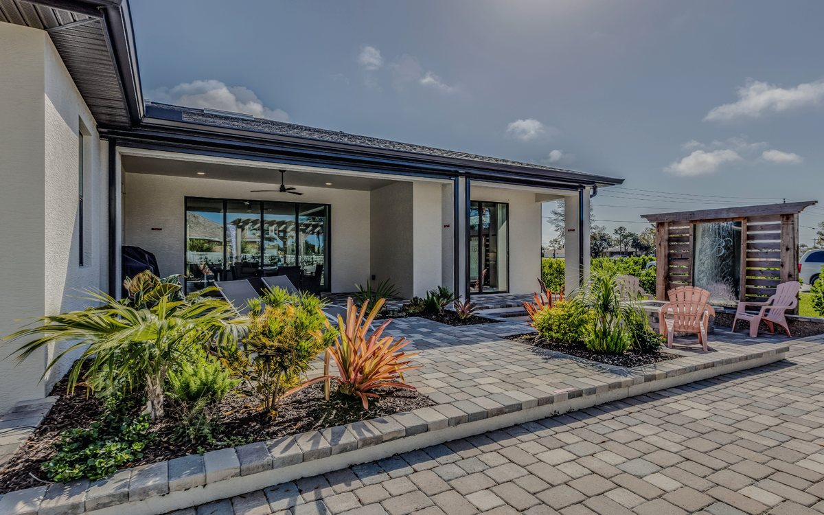 Paver patio and walkway laid behind a modern Santa Clarita home, bordered by drought tolerant planting