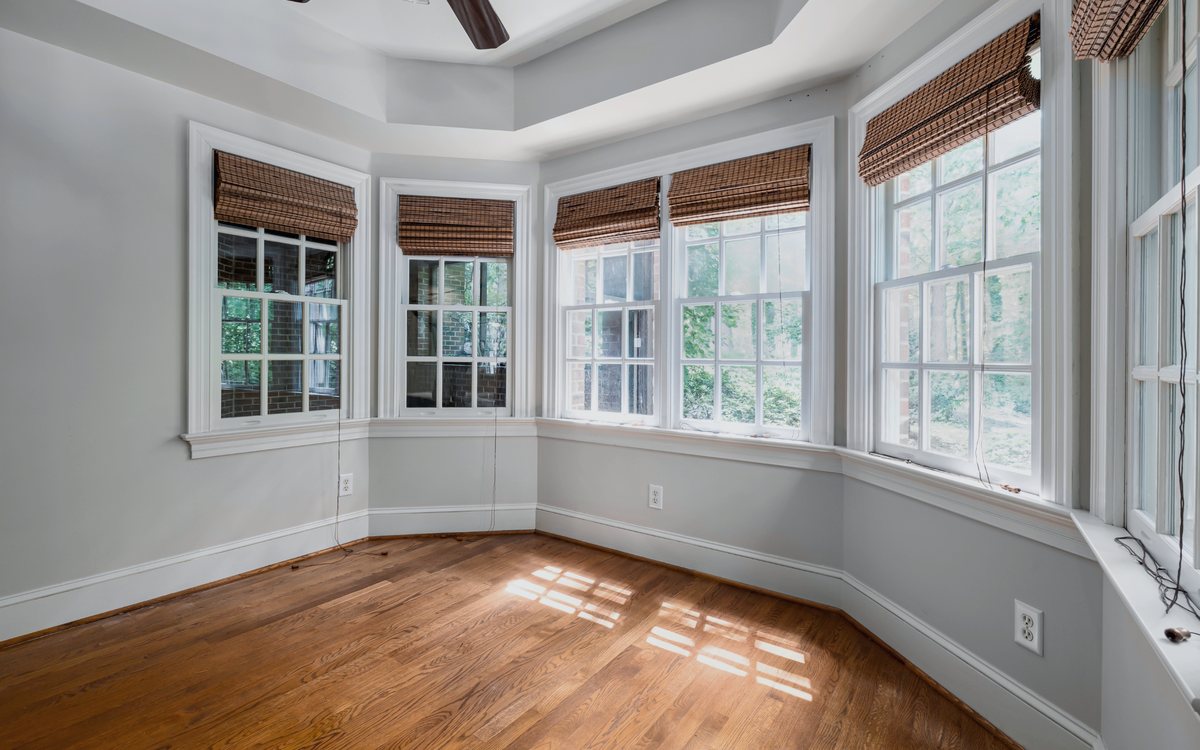 Bay window seating area with new white framed windows filling the room with afternoon light over a hardwood floor